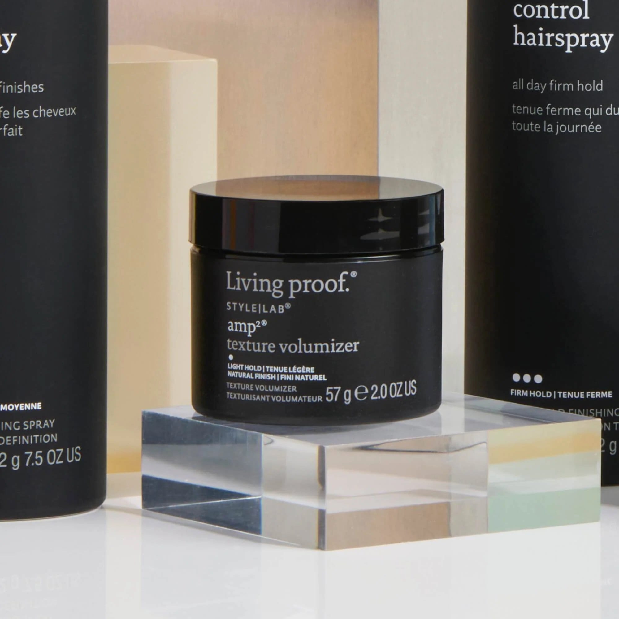 Amp2 Texture Volumizer jar on an acrylic block with Style Lab Flex Hairspray and Control Hairspray behind it