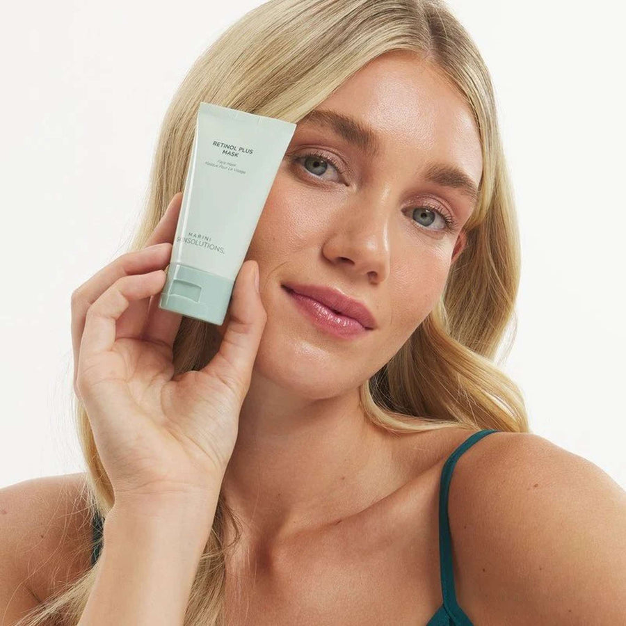Model holding Marini Skinsolutions Retinol Plus Mask sage green tube anti-aging face mask