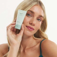 Model holding Marini Skinsolutions Retinol Plus Mask sage green tube anti-aging face mask