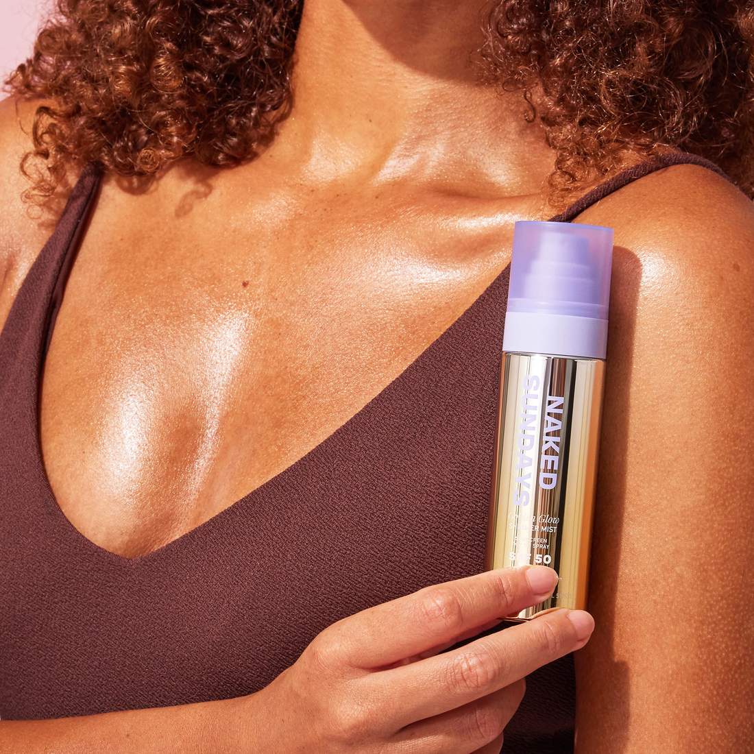 Naked Sundays Golden Glow Shimmer Mist SPF50 bottle held against a sun kissed shoulder