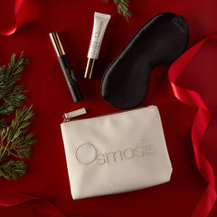 Osmosis Merry and Bright Eye Kit styled on a red background with pine branches and ribbon