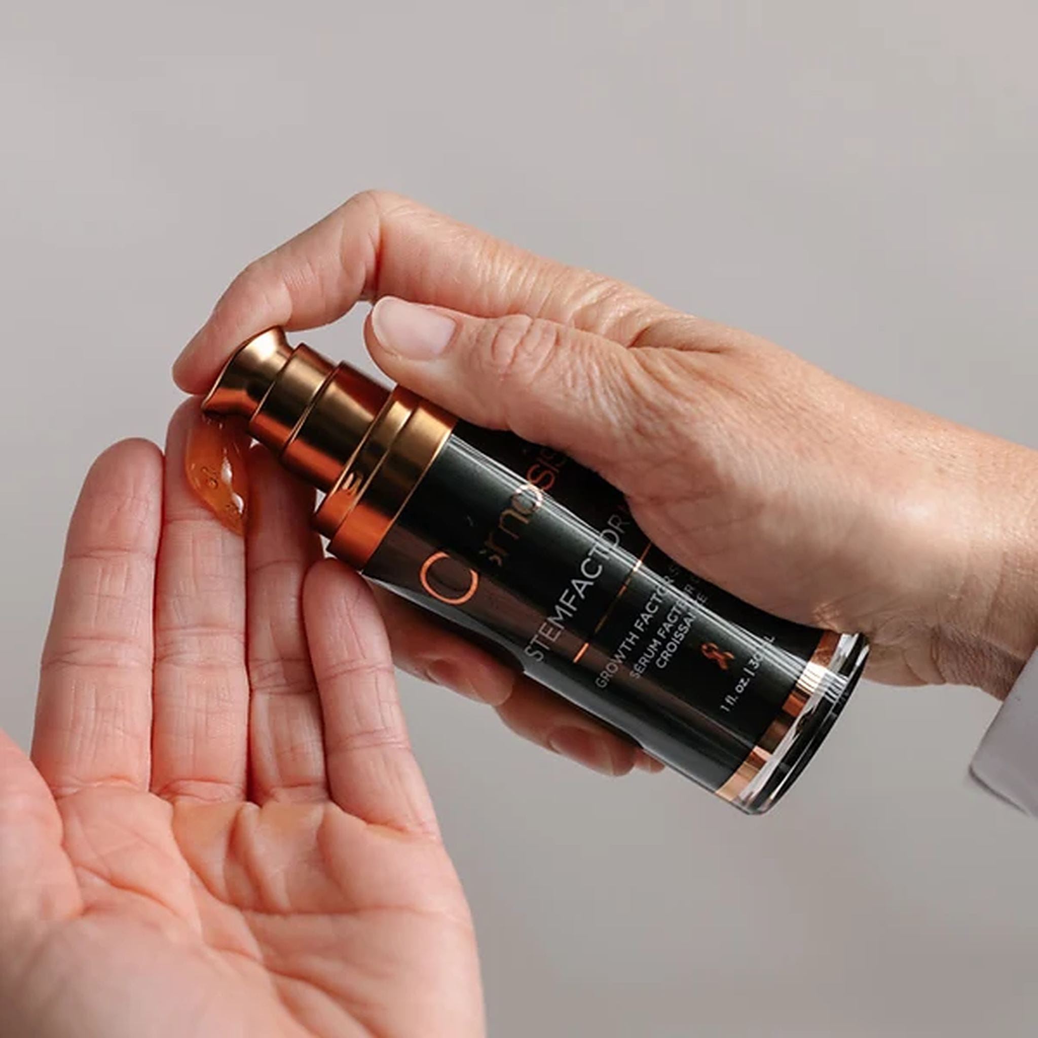 Hand pumping Osmosis StemFactor MD growth factor serum into palm for anti-aging skincare routine