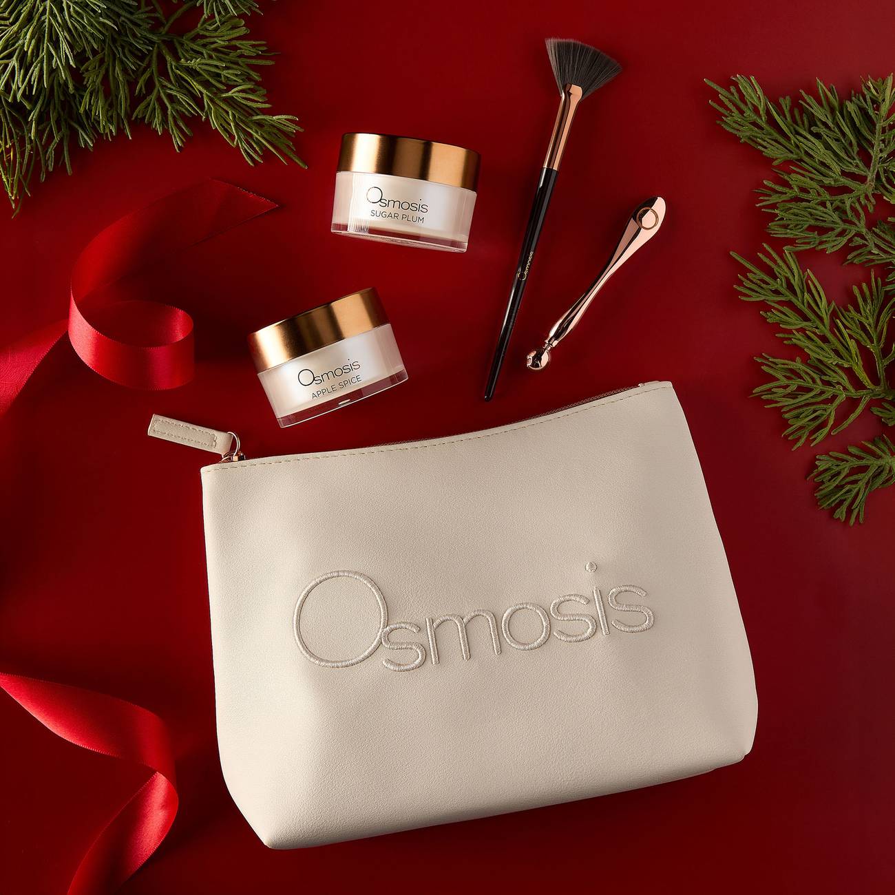 Osmosis Sugar and Spice Mask Set styled on a red background with pine branches and ribbon