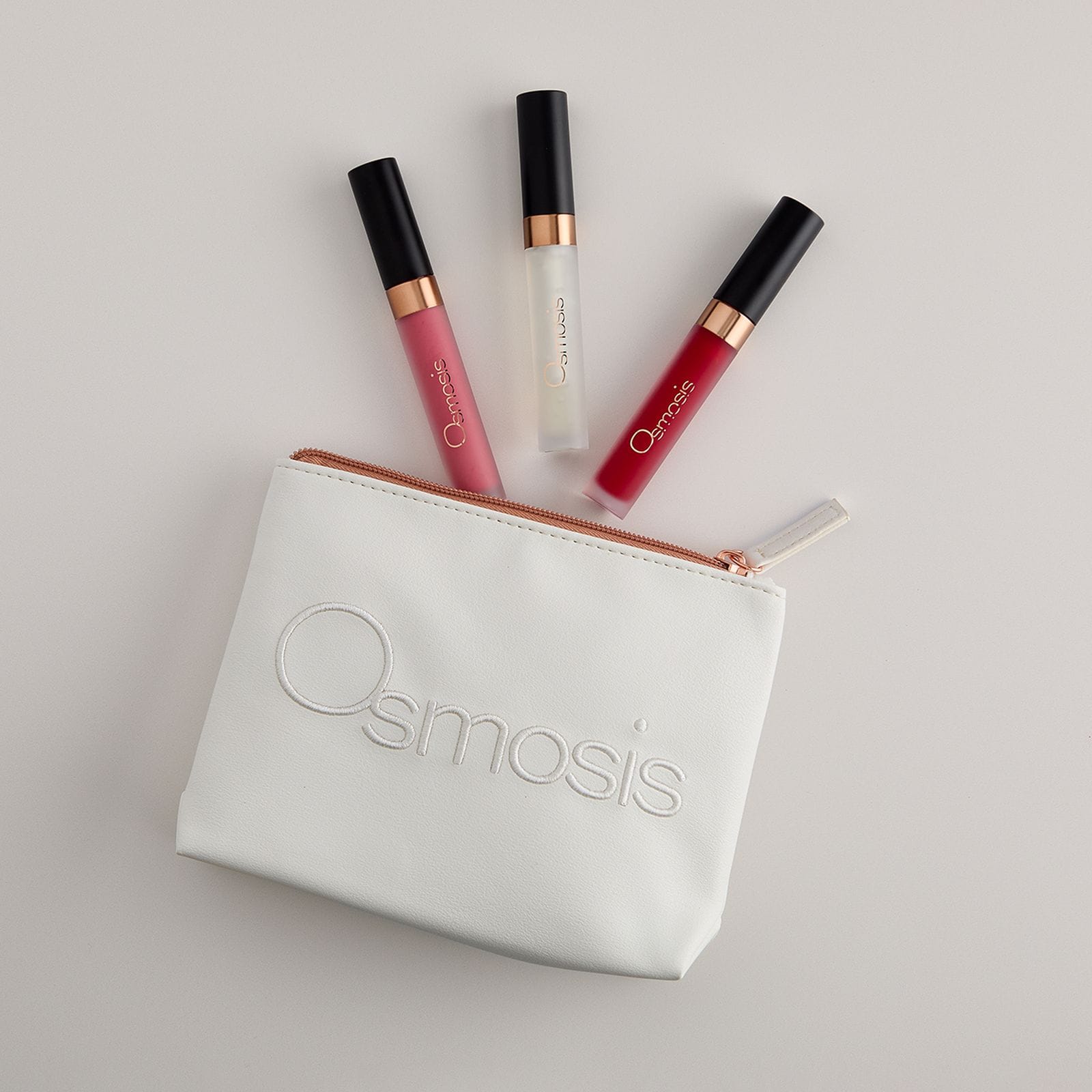 Osmosis Under the Mistletoe Lip Kit with three lip glosses and cosmetic bag on a white background