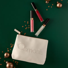 Osmosis Under the Mistletoe Lip Kit styled on a green background with gold ornaments and confetti