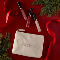 Osmosis Under the Mistletoe Lip Kit styled on a red background with pine branches and ribbon