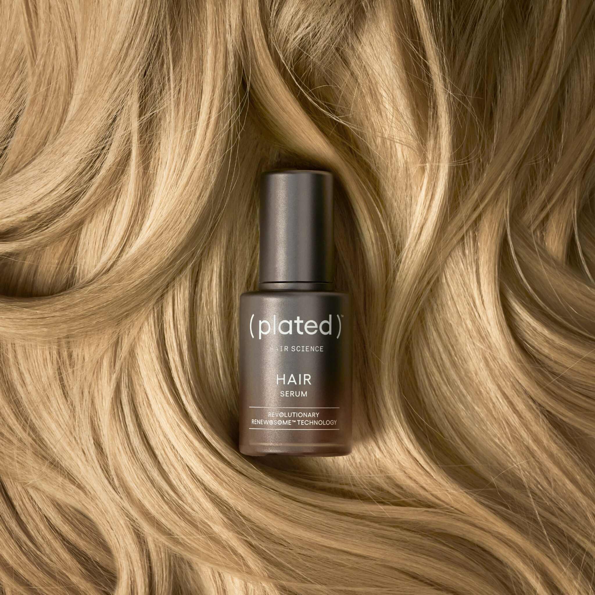 Plated Hair Serum bottle laid on flowing blonde hair strands