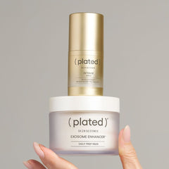 Plated Intense Serum stacked on Exosome Enhancer Daily Prep Pads jar balanced in a hand on gray backdrop 
