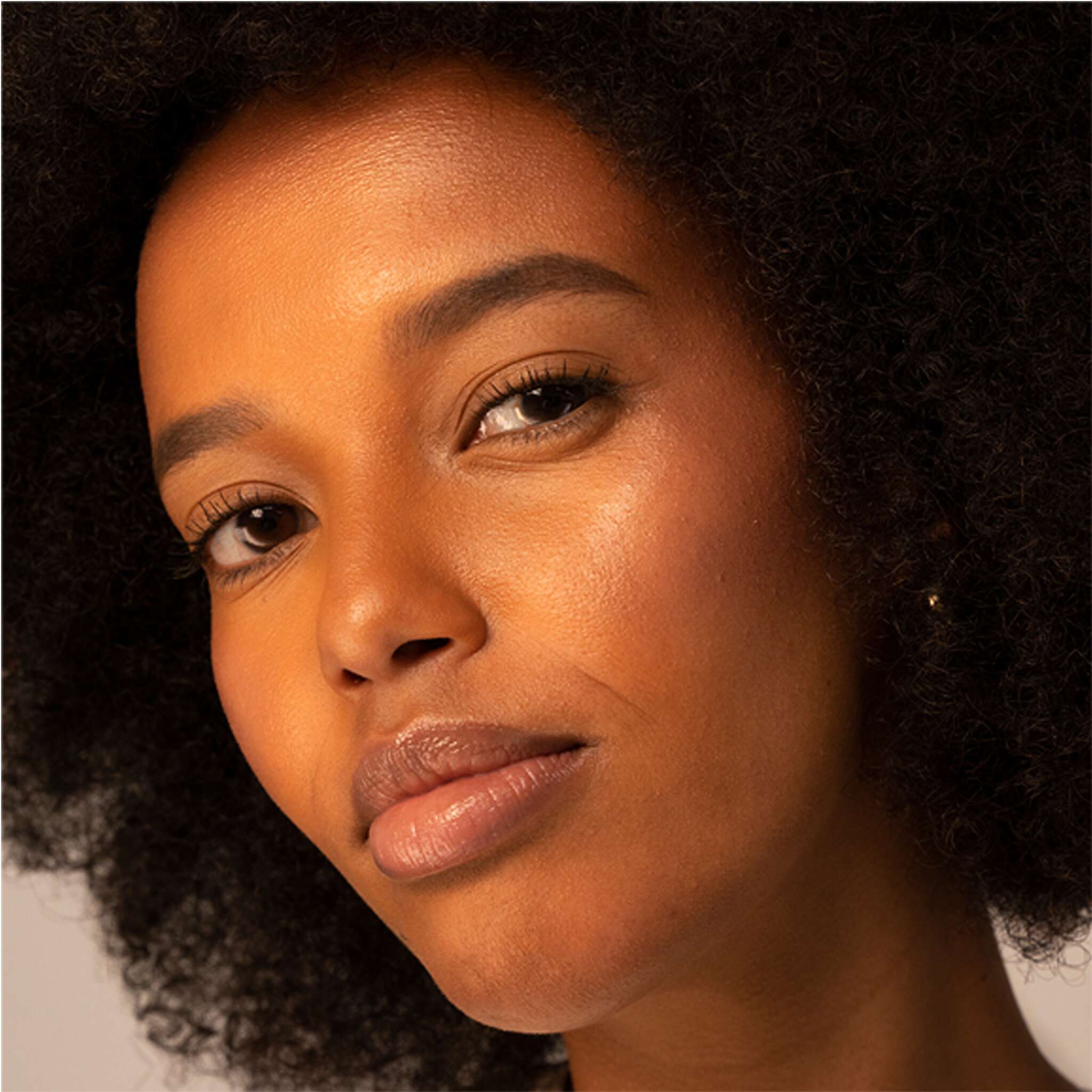 Model with deep skin tone wearing luminous bronzer highlight
