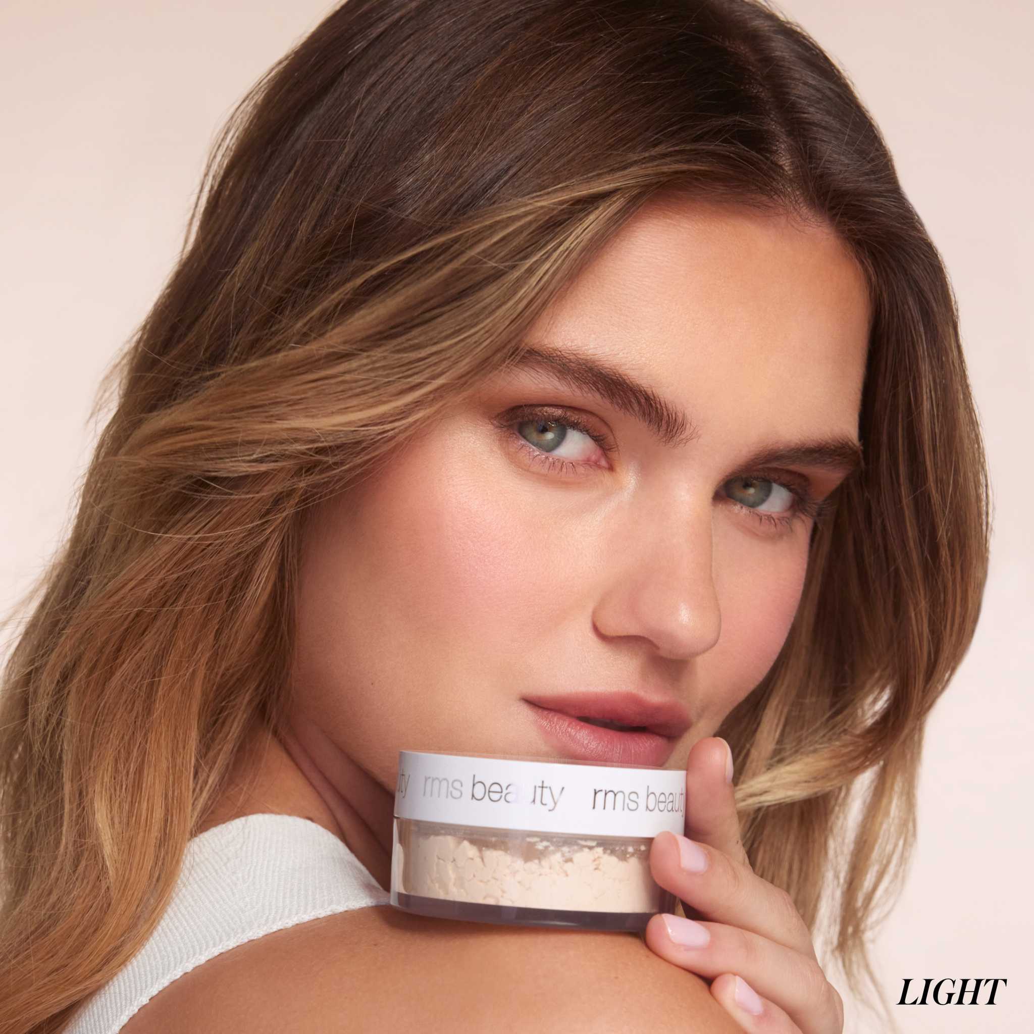 Model holding RMS Beauty Hydra Setting Powder jar in light shade 9