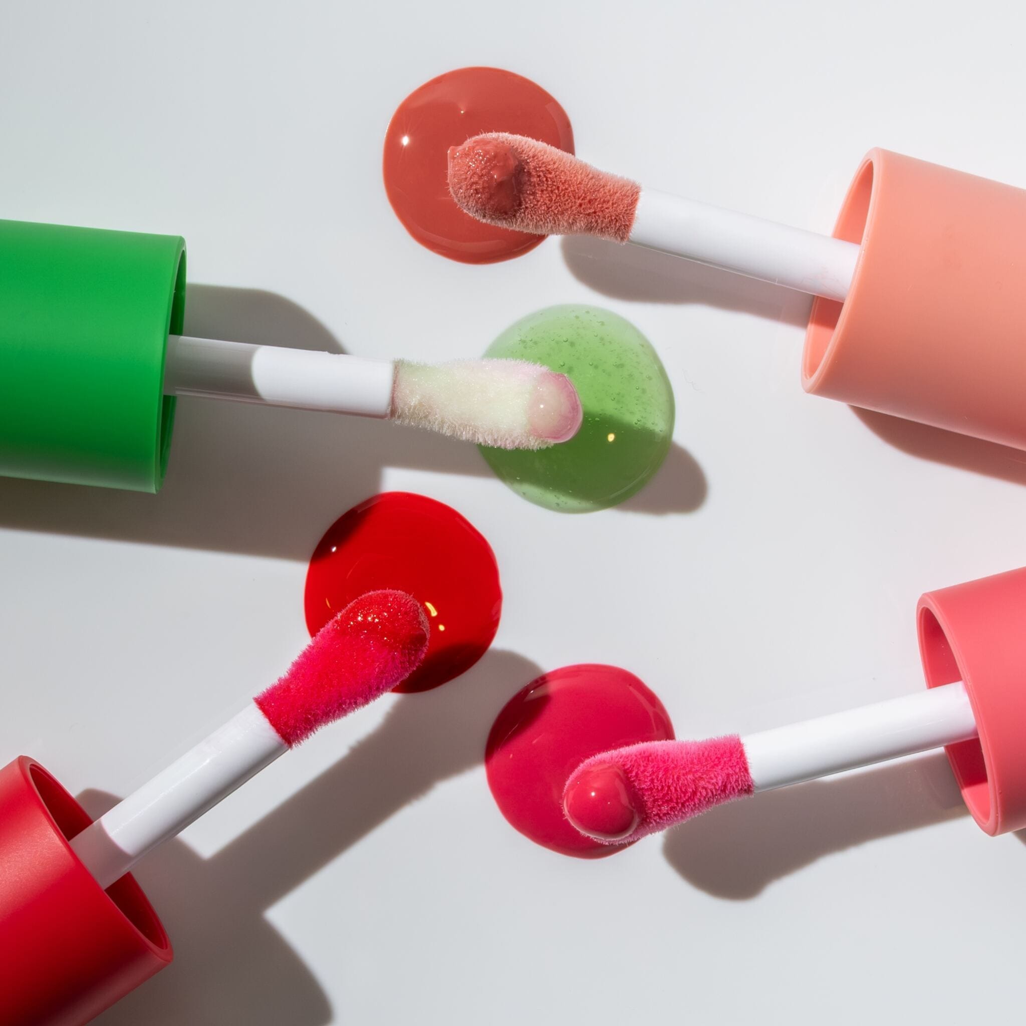 Lip oil applicator wands with color swatches in coral green and red 10