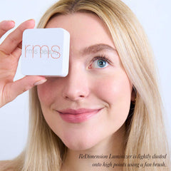 Model holding RMS Beauty ReDimension Hydra Dew highlighter compact near her eye 5