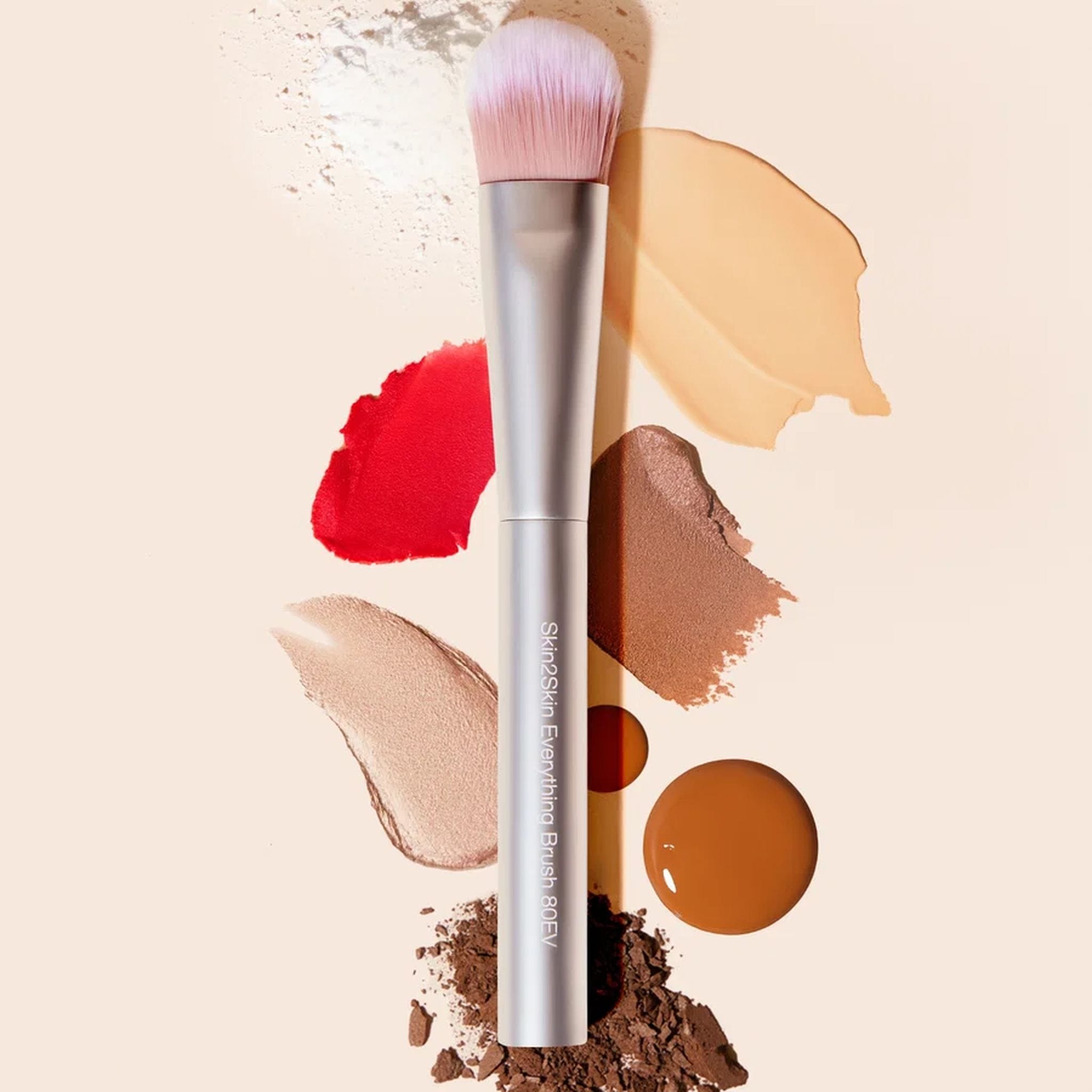 Skin2Skin Everything Brush surrounded by lipstick foundation and bronzer swatches