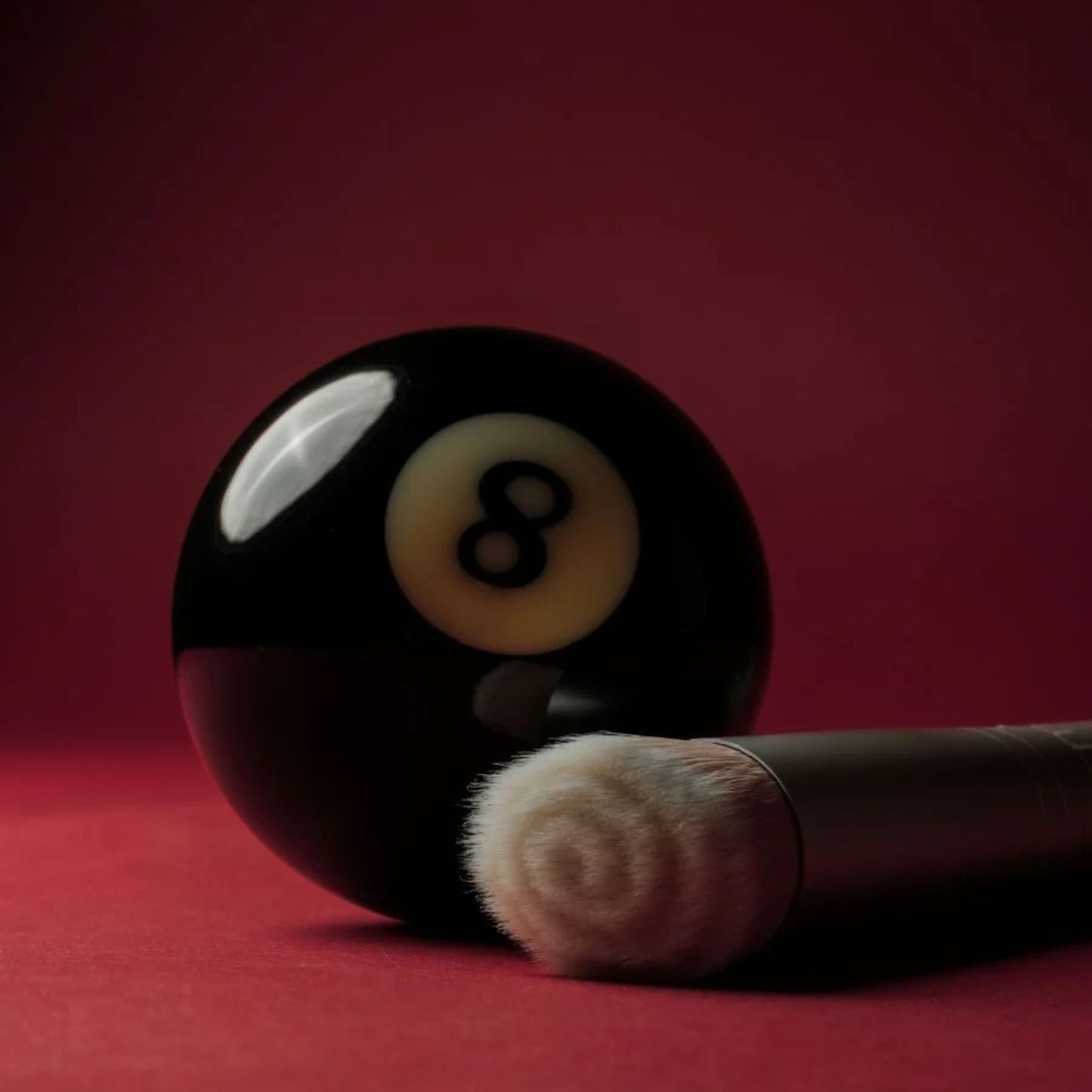 Skin2Skin foundation brush resting against an eight ball on red background