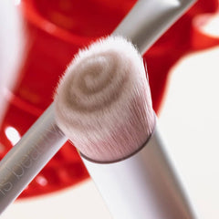 Close up of Skin2Skin foundation brush bristles with red backdrop