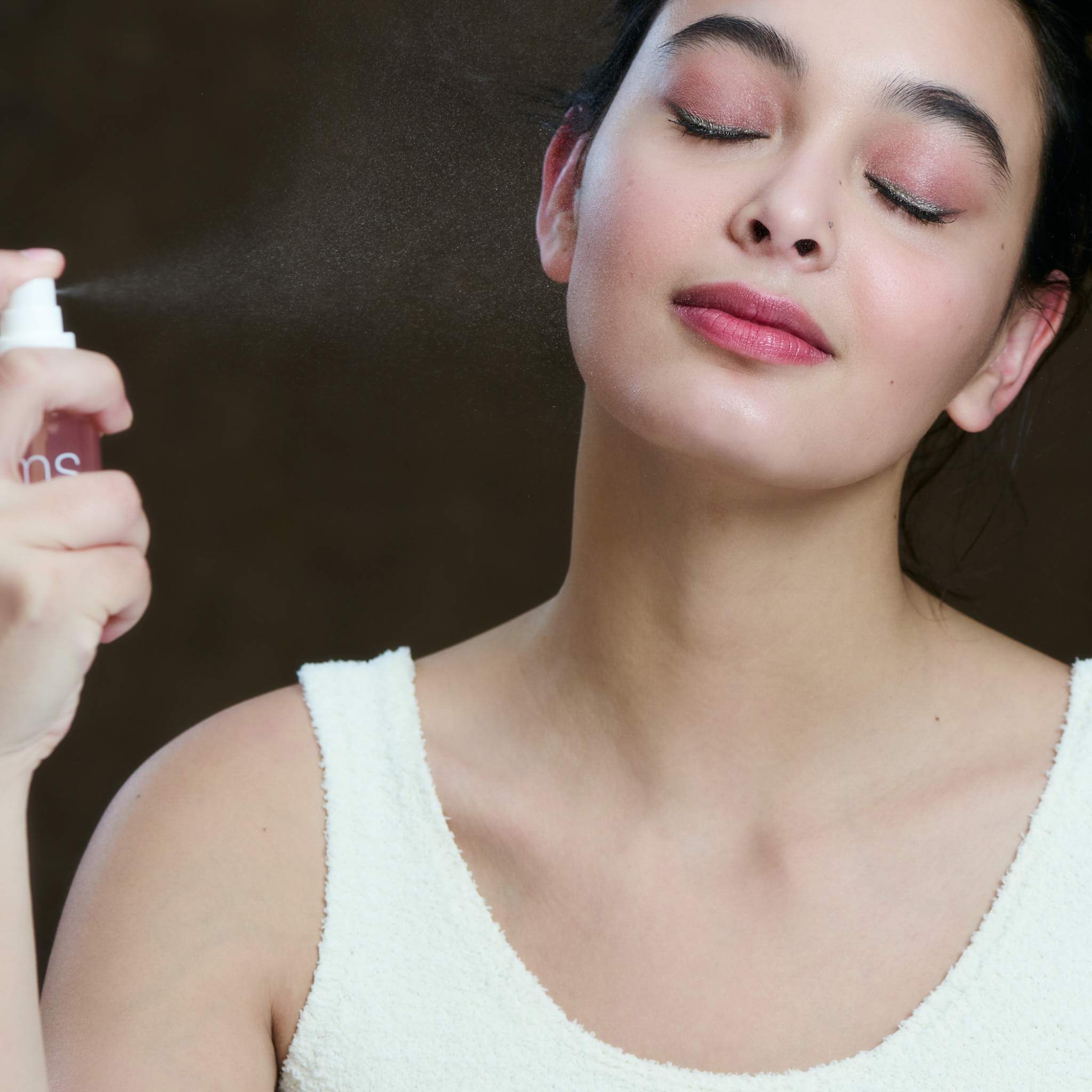 Model spraying Radiance Lock Setting Mist onto her face with eyes closed