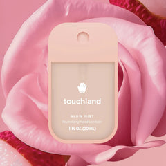 Touchland Glow Mist Rosewater hand sanitizer resting on a soft pink rose with peeled lychee