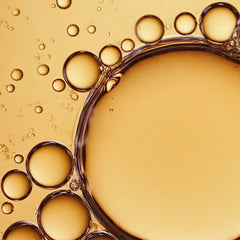 Close-up macro view of golden postbiomic face oil bubbles from Symbiome Rebalance001