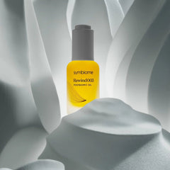Symbiome Rewind003 Postbiomic Oil bottle nestled among white sculptural botanical forms
