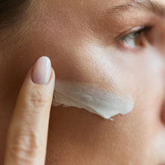 Woman applying Symbiome The One Restorative Cream to cheek with fingertip showing hydrating skin-care ritual