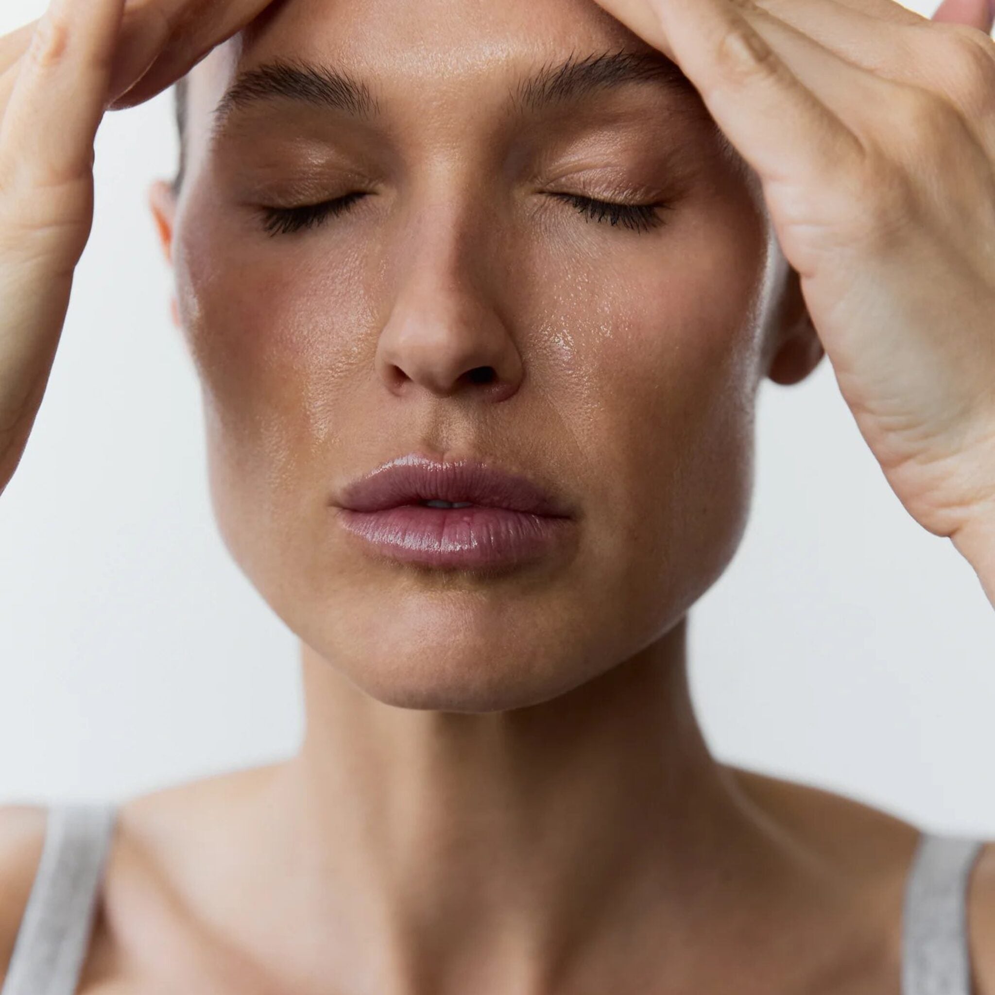 Woman applying Symbiome The Reset Clarifying Cleanser to face with fingertips