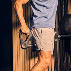 Man using Theragun Prime massage gun on his knee during a gym recovery session