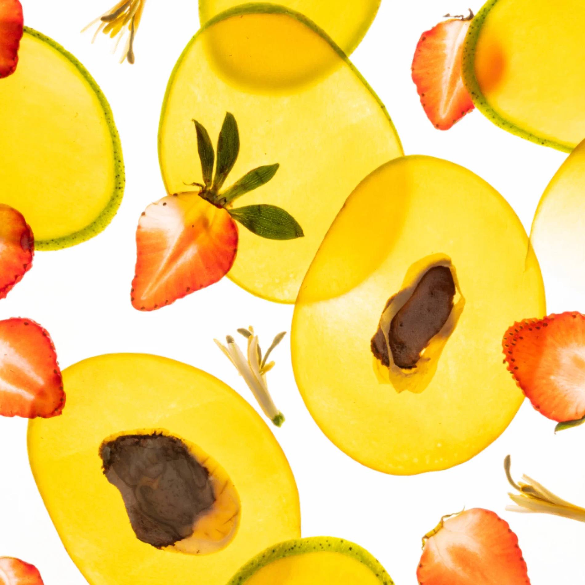 Sliced mango and strawberries with honeysuckle blossoms representing the Mango Mojo fragrance notes
