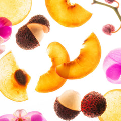 Juicy peach slices with peeled lychee and pink orchid blooms representing the Peachy Lychee fragrance notes