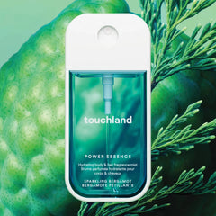 Touchland Power Essence Sparkling Bergamot fragrance mist against green bergamot fruit and cypress sprigs