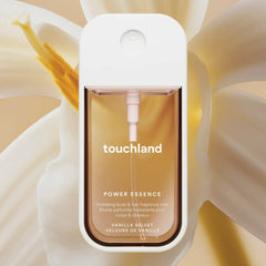 Touchland Power Essence Vanilla Velvet fragrance mist in front of a creamy vanilla orchid bloom